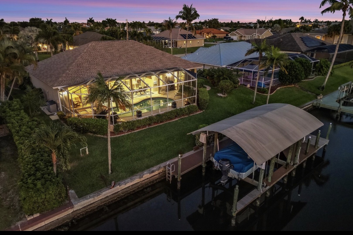 Aerial dusk view of the Cape Coral waterfront home with pool and private dock